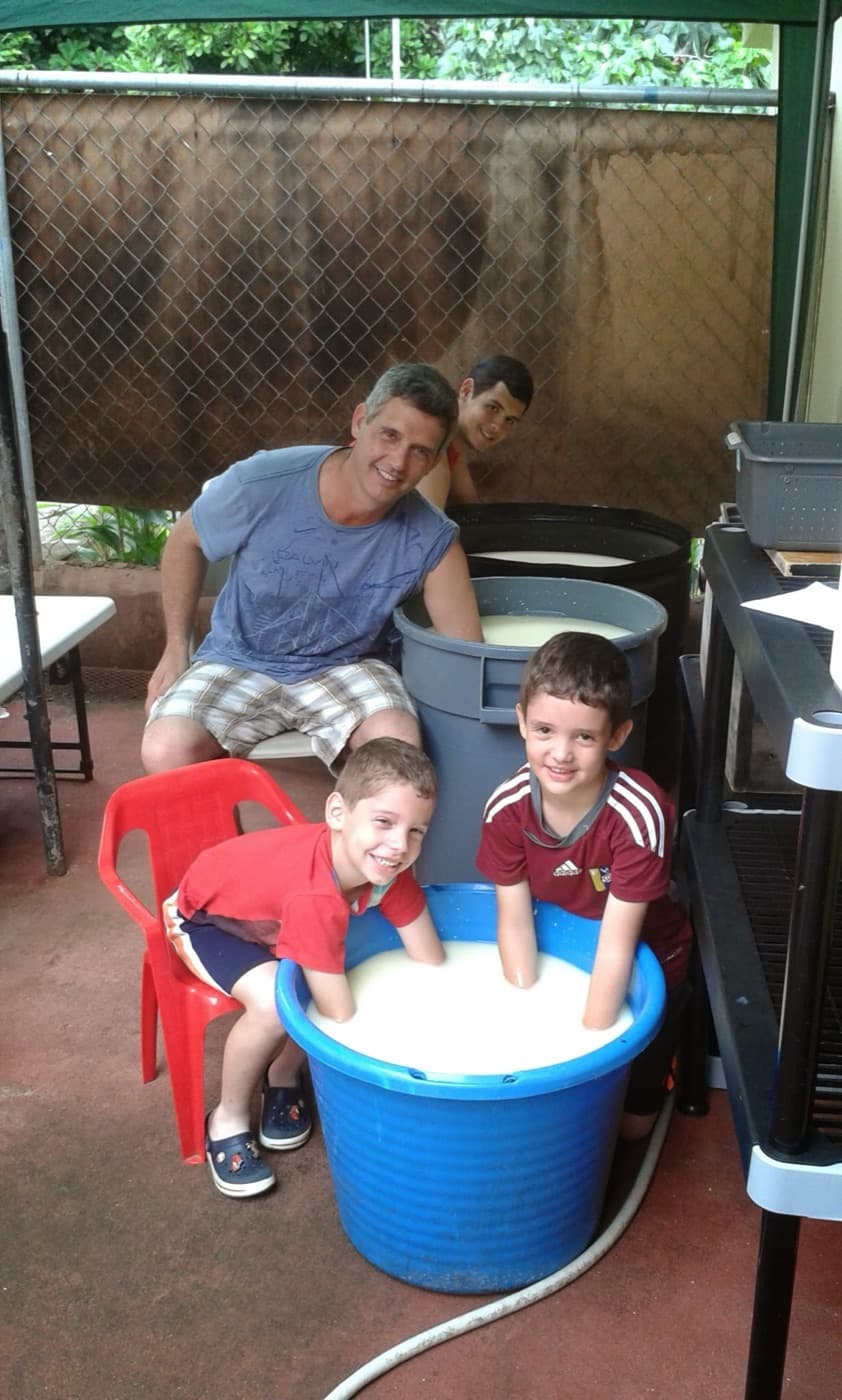 Un adulto y tres niños sonríen alrededor de una tina de leche en el garaje, en 2014